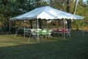 Anchor Industries 20x30 All Purpose Canopy with several tables, chairs and disposable plastic table covers.